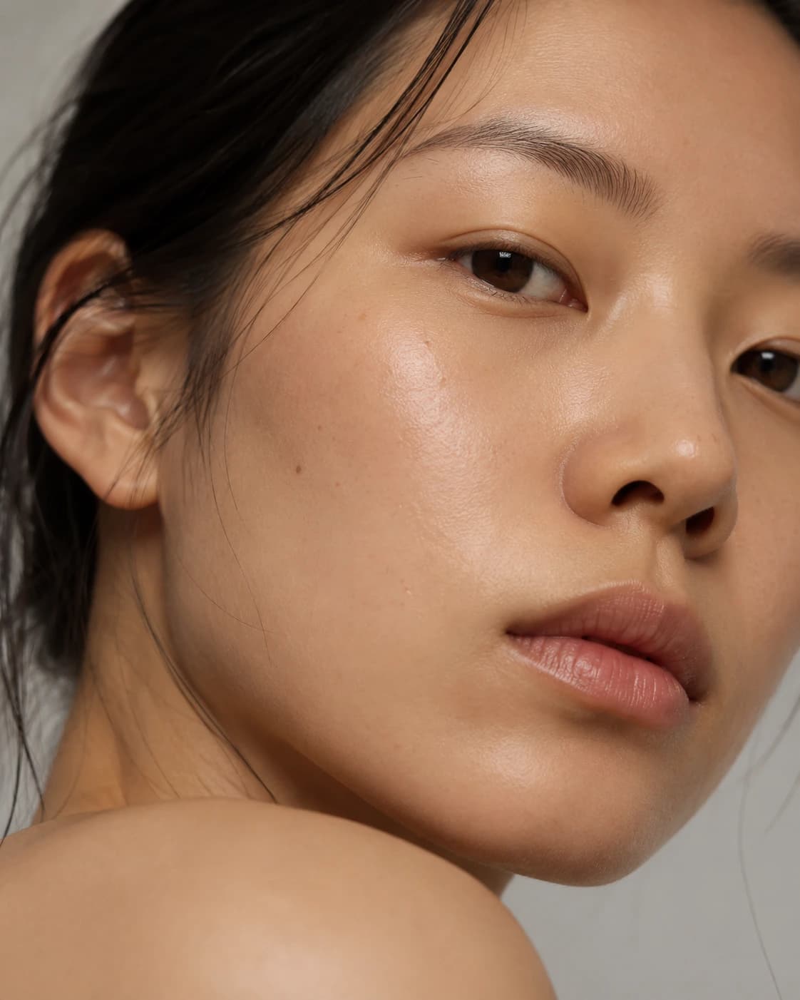 Beauty-campaign portrait — luminous, bare skin in soft studio light