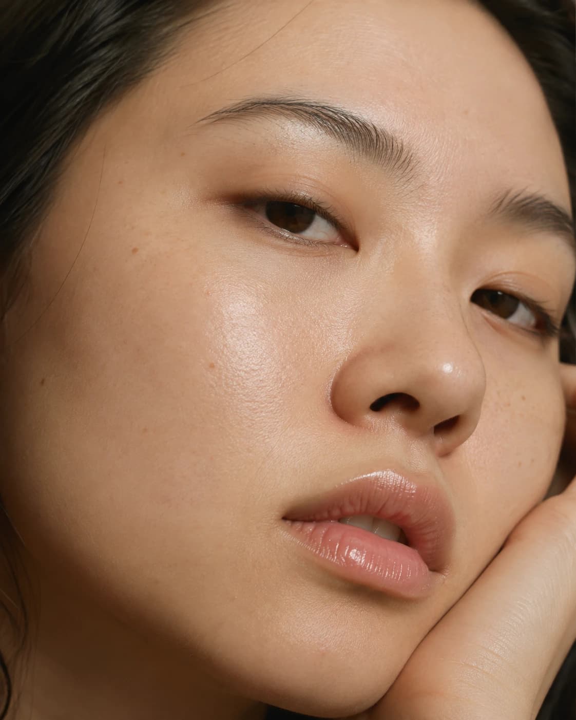 Close editorial crop of clear, luminous skin under soft light.